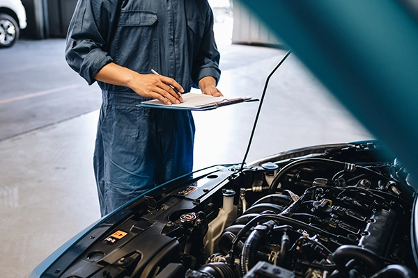 Technician inspecting vehicle with clipboard